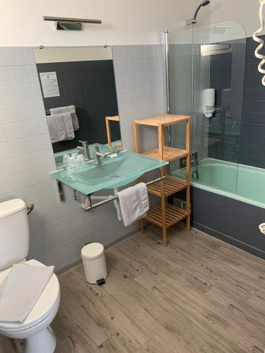 a bathroom with a sink and a toilet and a tub at Hôtel le Canetois in Canet-en-Roussillon