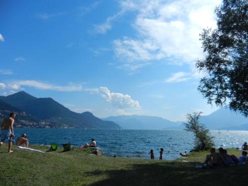 a group of people sitting on the shore of a lake at Casa Nora in Dervio