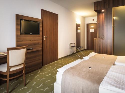 a hotel room with a bed and a desk and a television at Zenit Wellness Hotel Balaton in Vonyarcvashegy