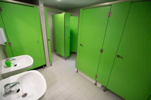 a bathroom with green stalls and a sink at Alberg Vall d'Àger in Àger