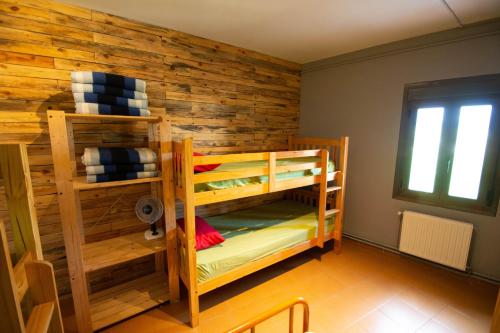 a room with two bunk beds and a wooden wall at Alberg Vall d'Àger in Àger