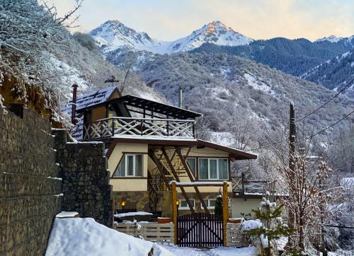 a house in the snow with mountains in the background at Dobri Dom in Almaty
