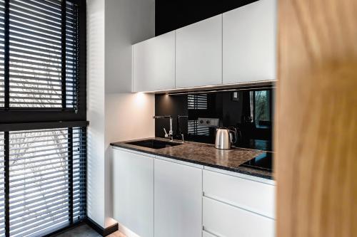 a kitchen with white cabinets and a sink at PLATiNIUM RESIDENCE&SPA BASEN-SAUNA "BEST VIEW" CENTER in Lublin