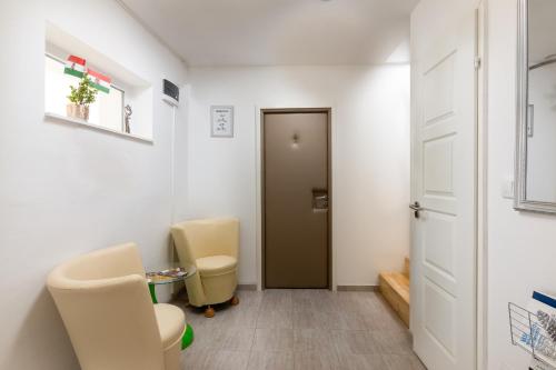 a room with two chairs and a door at Kőszeg Panzió in Kőszeg