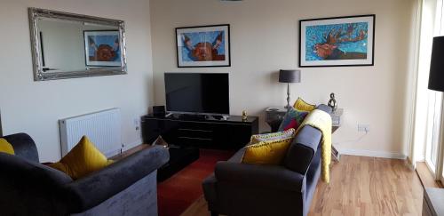 a living room with two couches and a flat screen tv at Aber Holiday Rentals in Inverness
