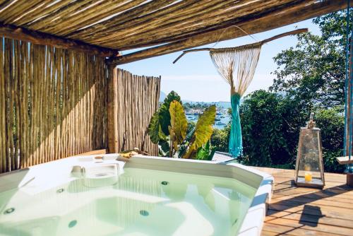 a bath tub on a deck with a view of the ocean at Vila Bambu Ilhabela, Santa Tereza in Ilhabela
