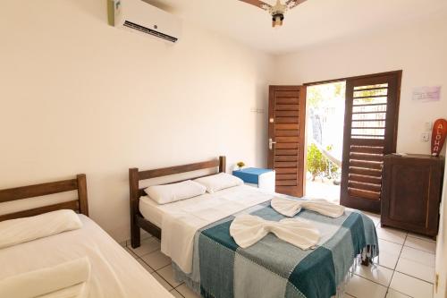 1 Schlafzimmer mit 2 Betten und einer Tür zu einer Terrasse in der Unterkunft Surfcamp Arara in Pipa