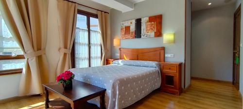 a bedroom with a bed and a table and a window at Hotel Rural la Plaza in Caso