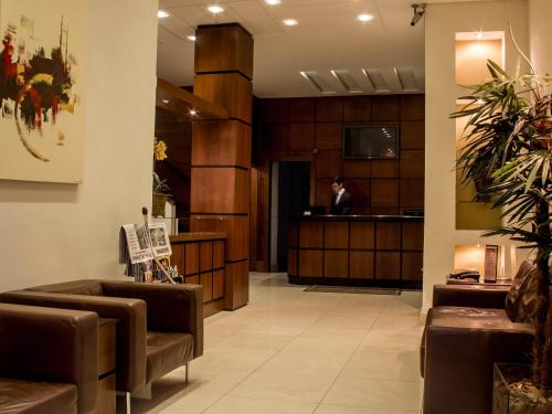 a lobby with a waiting room with a person in the background at Hotel Brasilia Curitiba in Curitiba