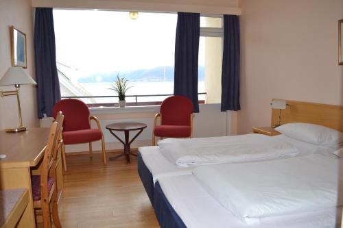 a hotel room with a bed and a desk and chairs at Midtnes Hotel in Balestrand