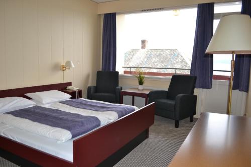 um quarto de hotel com uma cama e duas cadeiras e uma janela em Midtnes Hotel em Balestrand