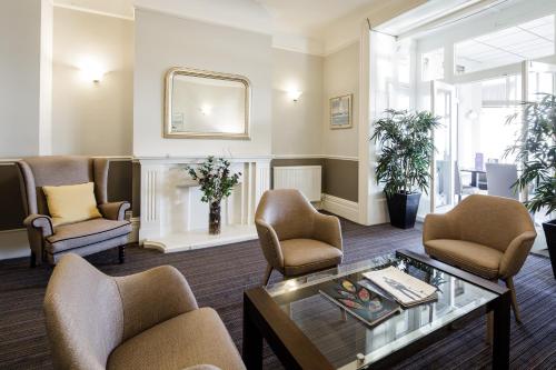 a waiting room with chairs and a table and a mirror at Ommaroo Hotel in Saint Helier Jersey