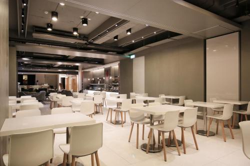 una sala da pranzo con tavoli e sedie bianchi di Dandy Hotel-Daan Park Branch a Taipei