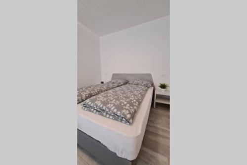 uma cama branca num quarto com uma parede branca em Appartamento ZIMA em Malcesine