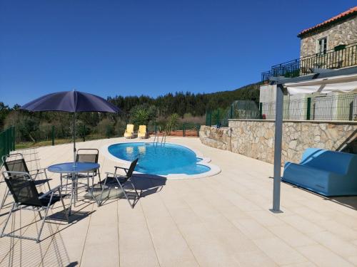 a patio with a table and chairs and an umbrella at Casa De Campo De Oliveiras in Penela