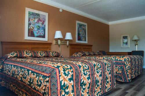 a hotel room with two beds with colorful blankets at America's Inn Houston/Stafford /Sugarland in Houston