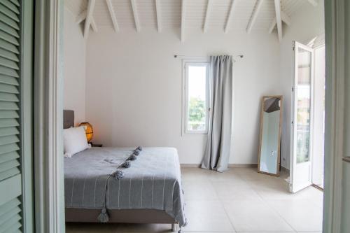 a white bedroom with a bed and a window at Life is Good in SXM in Saint Martin