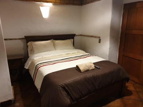a bedroom with a bed with a brown ottoman next to it at Casona Real Santa Barbara in Ráquira