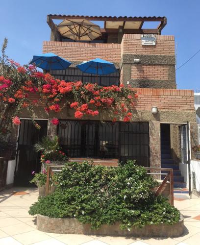 a building with red flowers and blue umbrellas at Bungalows Cerro Azul in Cerro Azul