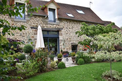 a house with a garden and an umbrella at La Grange Bagnolaise in Bagnoles de l'Orne