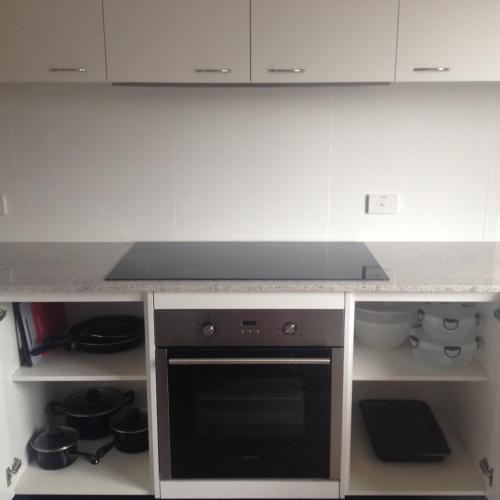 a kitchen with a stove and white cabinets at Comfort Inn Serenity Bathurst in Bathurst