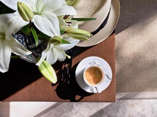 a cup of coffee and a vase with flowers on a table at The Diplomat Boutique Hotel in Mérida
