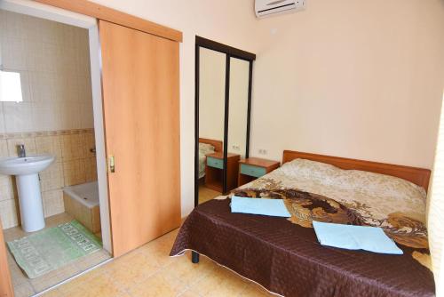 1 dormitorio con 1 cama y baño con lavamanos en Гостевой дом на Коллективной en Kabardinka