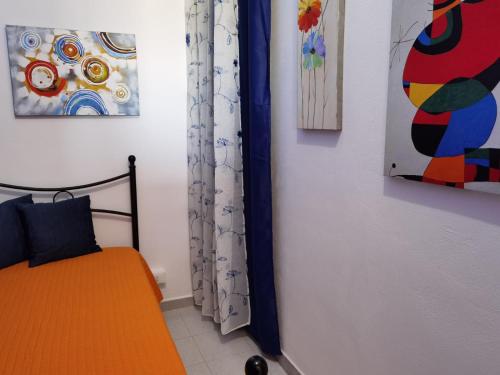 a bedroom with a bed and paintings on the wall at appartamento dei colori anticaglie in Punta Secca