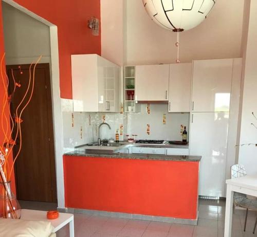 a kitchen with white cabinets and a red counter top at appartamento dei colori anticaglie in Punta Secca