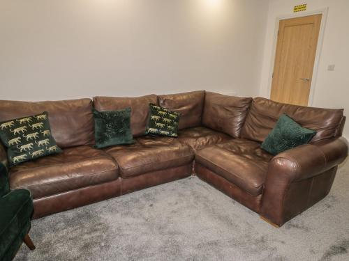 a brown leather couch in a living room with pillows at 47 Baxtergate in Whitby