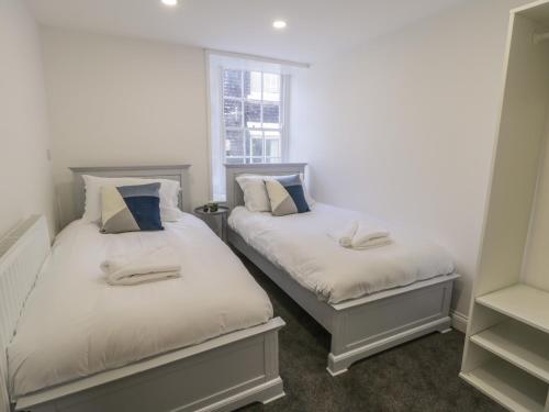 two twin beds in a room with a window at 47 Baxtergate in Whitby