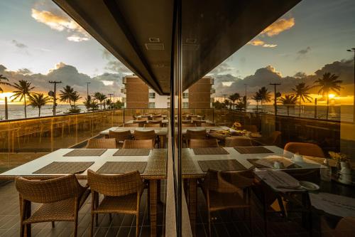 um restaurante com mesas e cadeiras e o oceano em Hardman Praia Hotel em João Pessoa