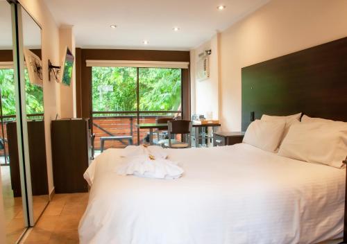 - une chambre avec un grand lit blanc et un balcon dans l'établissement Windmuhle Apart Hotel & Spa, à Villa General Belgrano