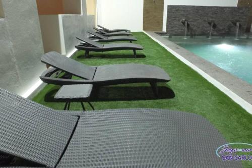 a row of benches sitting next to a swimming pool at Departamento Topacio 3 Joyas del Mar San Carlos in San Carlos