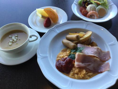 a table with plates of food and a cup of soup at Okazaki New Grand Hotel in Okazaki