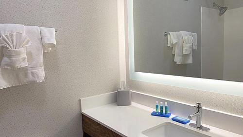 een badkamer met een wastafel, een spiegel en handdoeken bij Holiday Inn Express Hotel & Suites Columbia-Fort Jackson, an IHG Hotel in Columbia