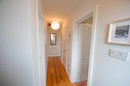 a hallway with white walls and wood floors and a light fixture at Beautiful coastal house at the Drowes Rivermouth in Bundoran