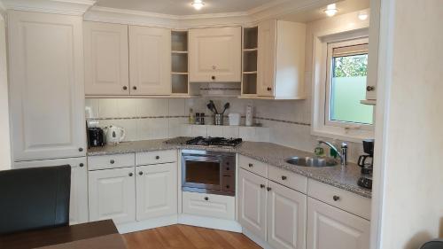 a white kitchen with white cabinets and a sink at Ruim familie chalet tot 4 personen op de Veluwe Bungalowpark De Kern in Putten