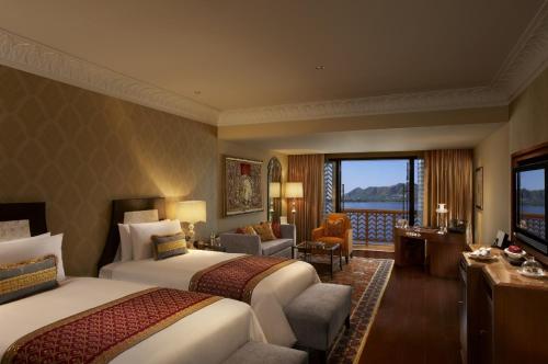 a hotel room with two beds and a living room at The Leela Palace Udaipur in Udaipur