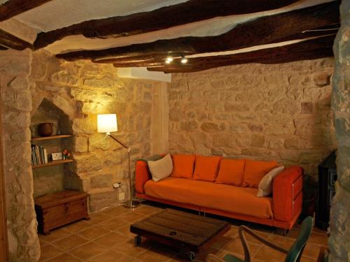 a living room with an orange couch in a stone wall at Alojamiento La Fresneda in La Fresneda