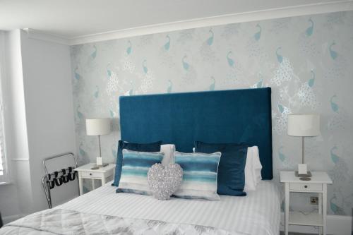 a bed with a blue headboard and two white tables at Harriet House B&B in Canterbury