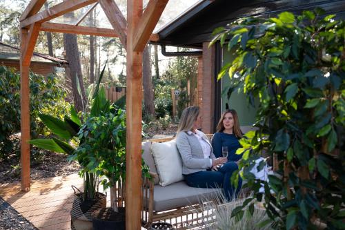 two women sitting on a couch on a patio at ZEN-bungalow NO 1 met sauna en hottub in Rheezerveen