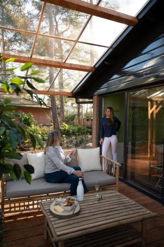 two women sitting on a bench on a patio at ZEN-bungalow NO 1 met sauna en hottub in Rheezerveen