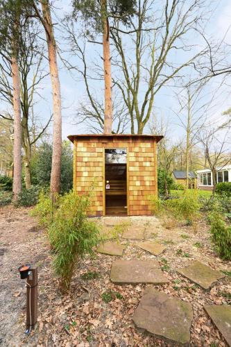 a small brick building in a yard with trees at ZEN-bungalow NO 1 met sauna en hottub in Rheezerveen