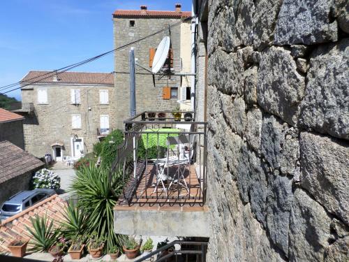 - un balcon avec une table et des chaises sur un mur dans l'établissement Appartement de charme entre mer et montagne, à Sollacaro