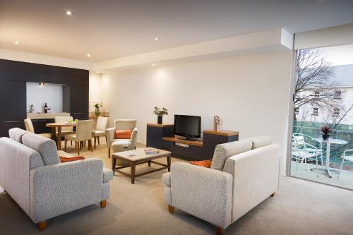 a living room with chairs and a tv and a table at The Sebel Launceston in Launceston
