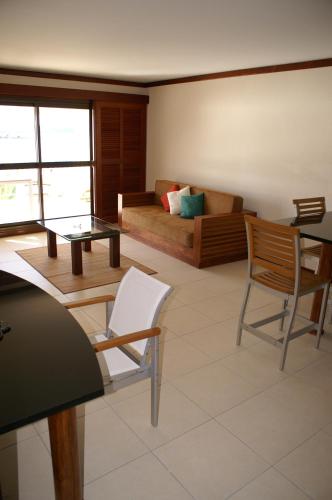 a living room with a couch and a table and chairs at Le Stanley Hôtel in Noumea
