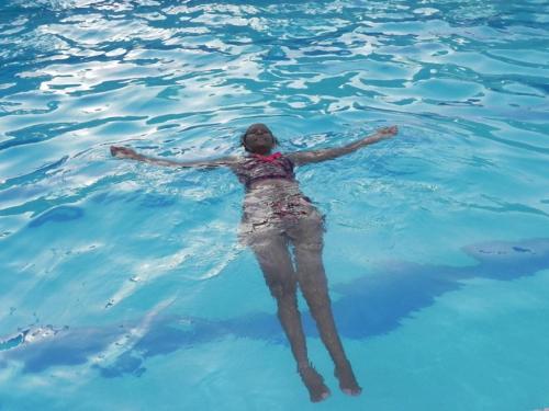 a woman floating in the water in the water at Prime Comfort HOTELS & Apartments Mtwapa in Mtwapa