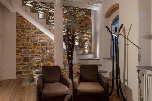two chairs in a room with a stone wall at old medieval apartment in San Donato in Poggio