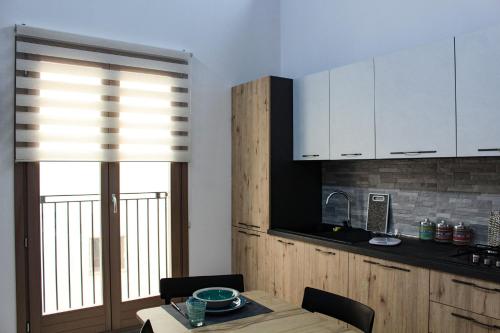 a kitchen with white cabinets and a table and a window at Suite Torre Pali in Trapani